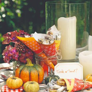 An autumn tablescape with a large candle and pumpkin decor
