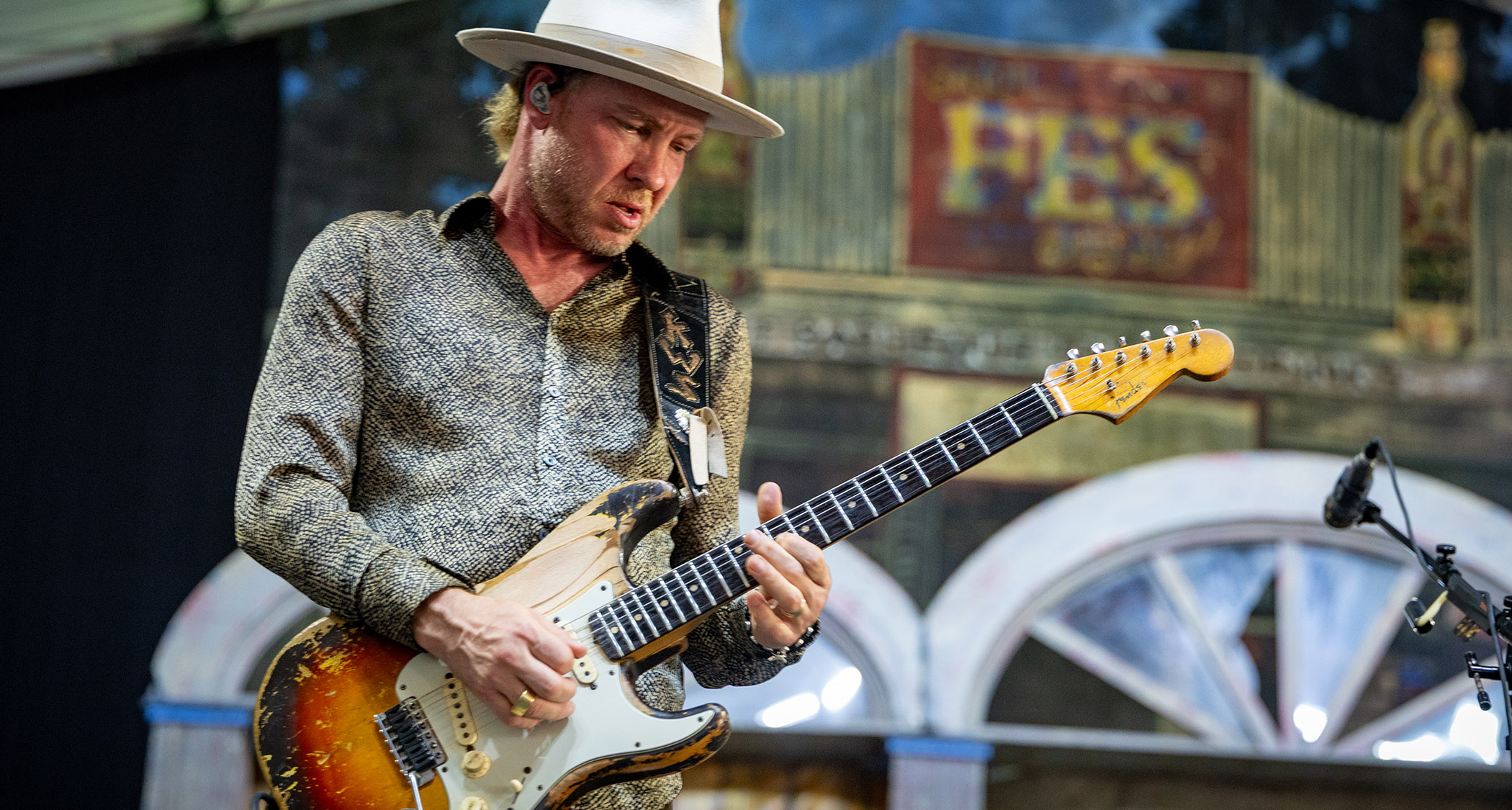 Kenny Wayne Shepherd plays a battered Fender Stratocaster onstage in New Orleans, 2025. He wears a cream Fedora and a patterned shirt.