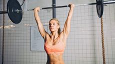 fit woman doing barbell clean press exercise 