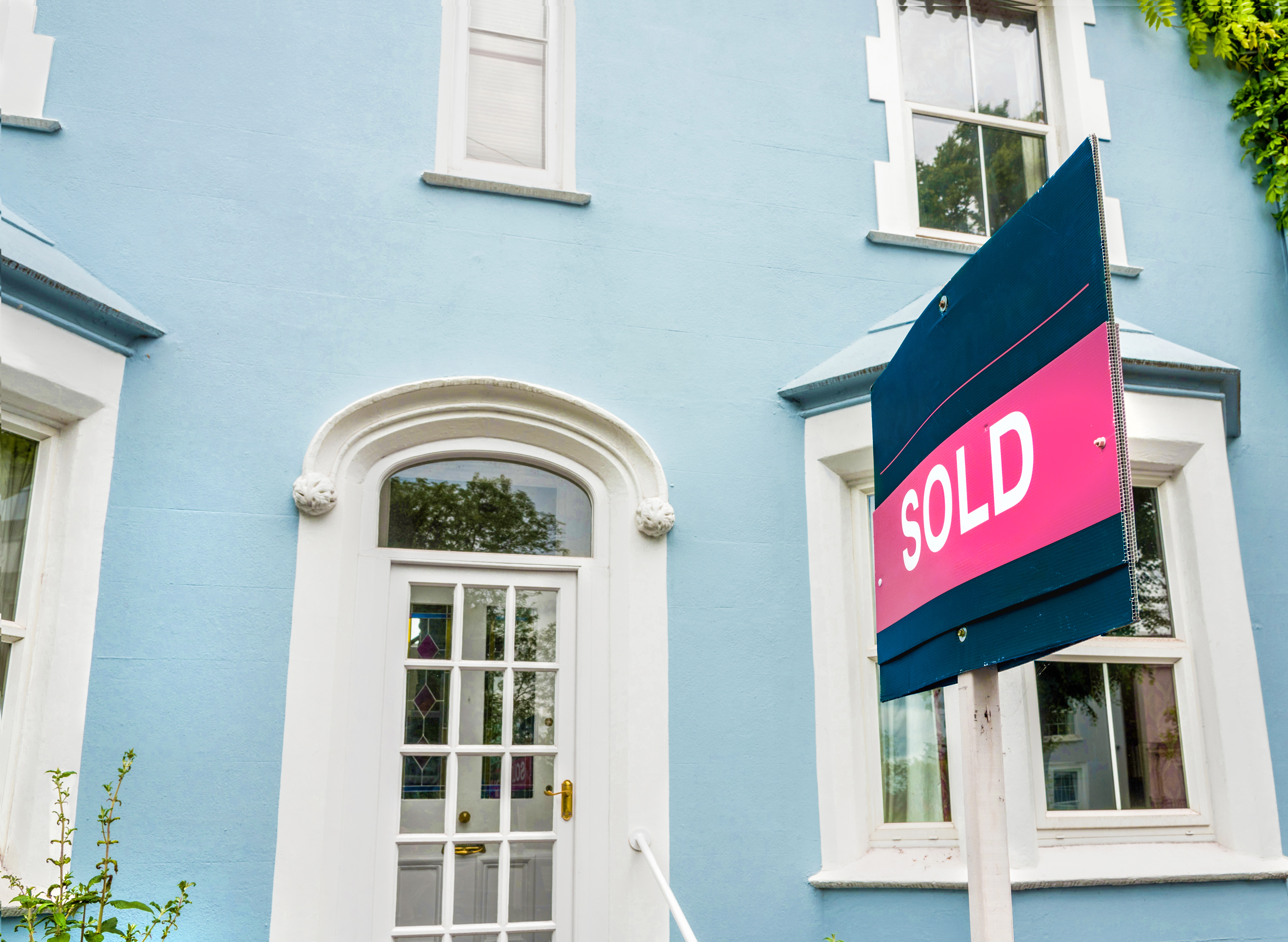 Sold sign outside a blue painted house which had been for sale.