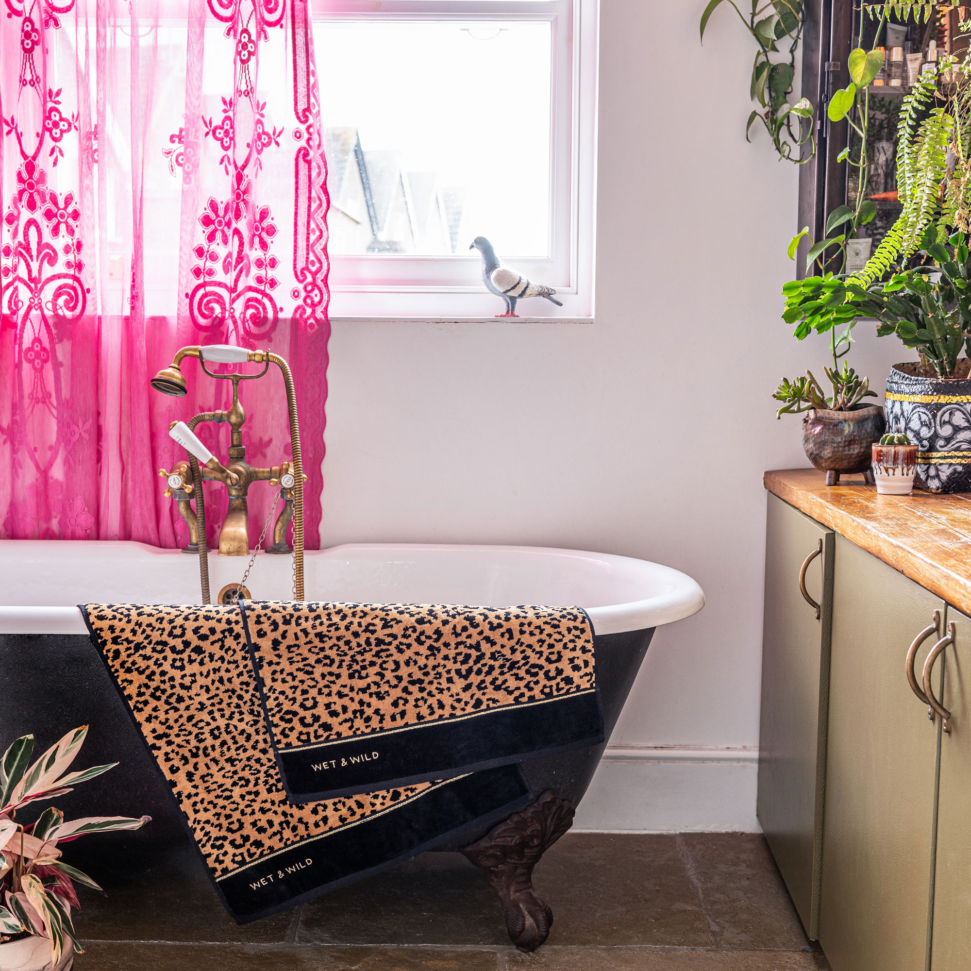 bathroom with pink net curtain and black freestanding bath