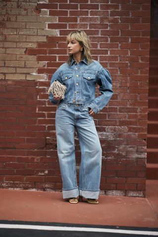 A woman at Fashion Week wearing baggy jeans with a jean jacket