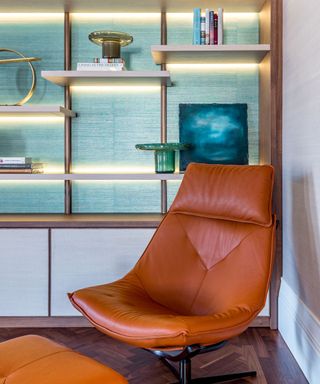Blue wall with shelving in front and leather armchair