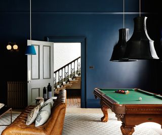 dark blue painted walls in room with large black pendant shade above pool table