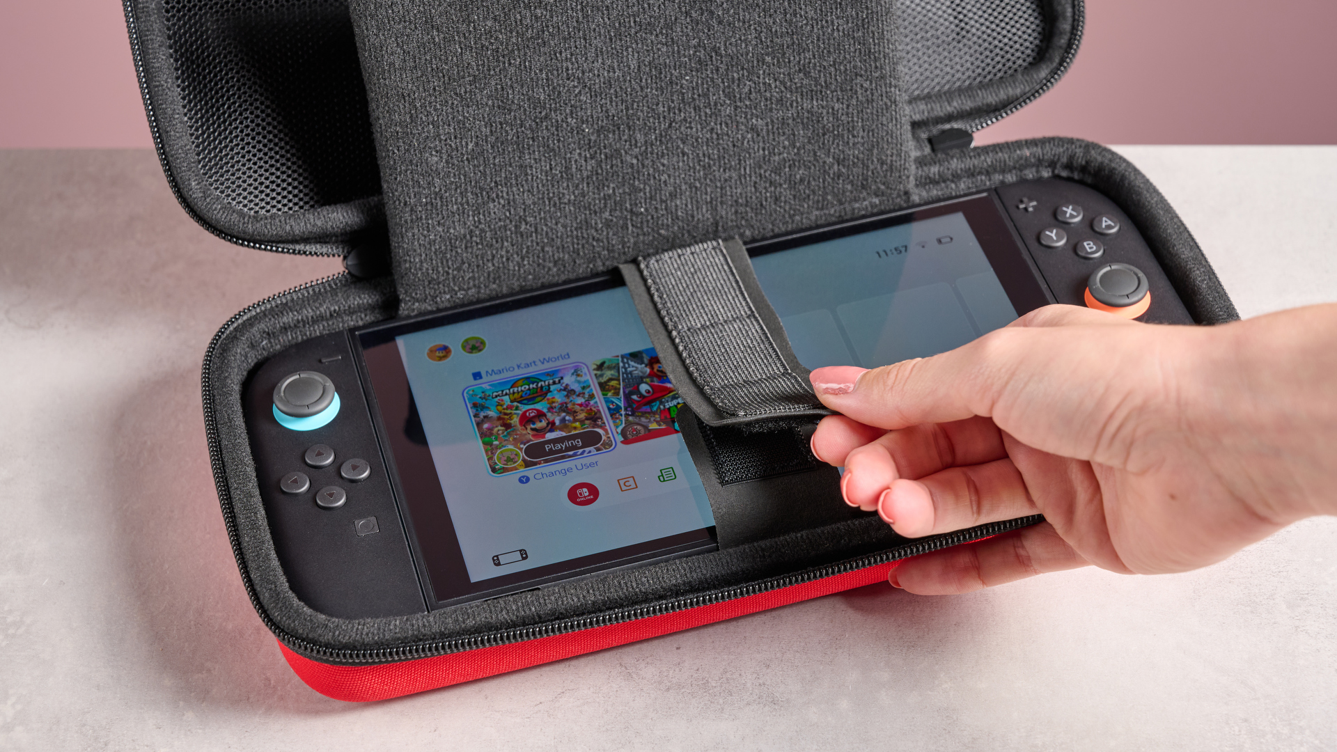 A woman's hand closing the cartridge-holding strap of the Nacon Hard Carrying Case for Nintendo Switch 2.