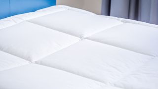 White mattress topper in blue bedroom