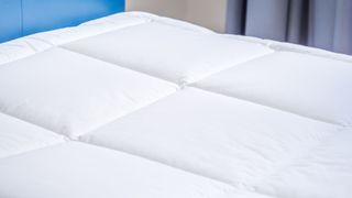 White mattress pad in blue bedroom