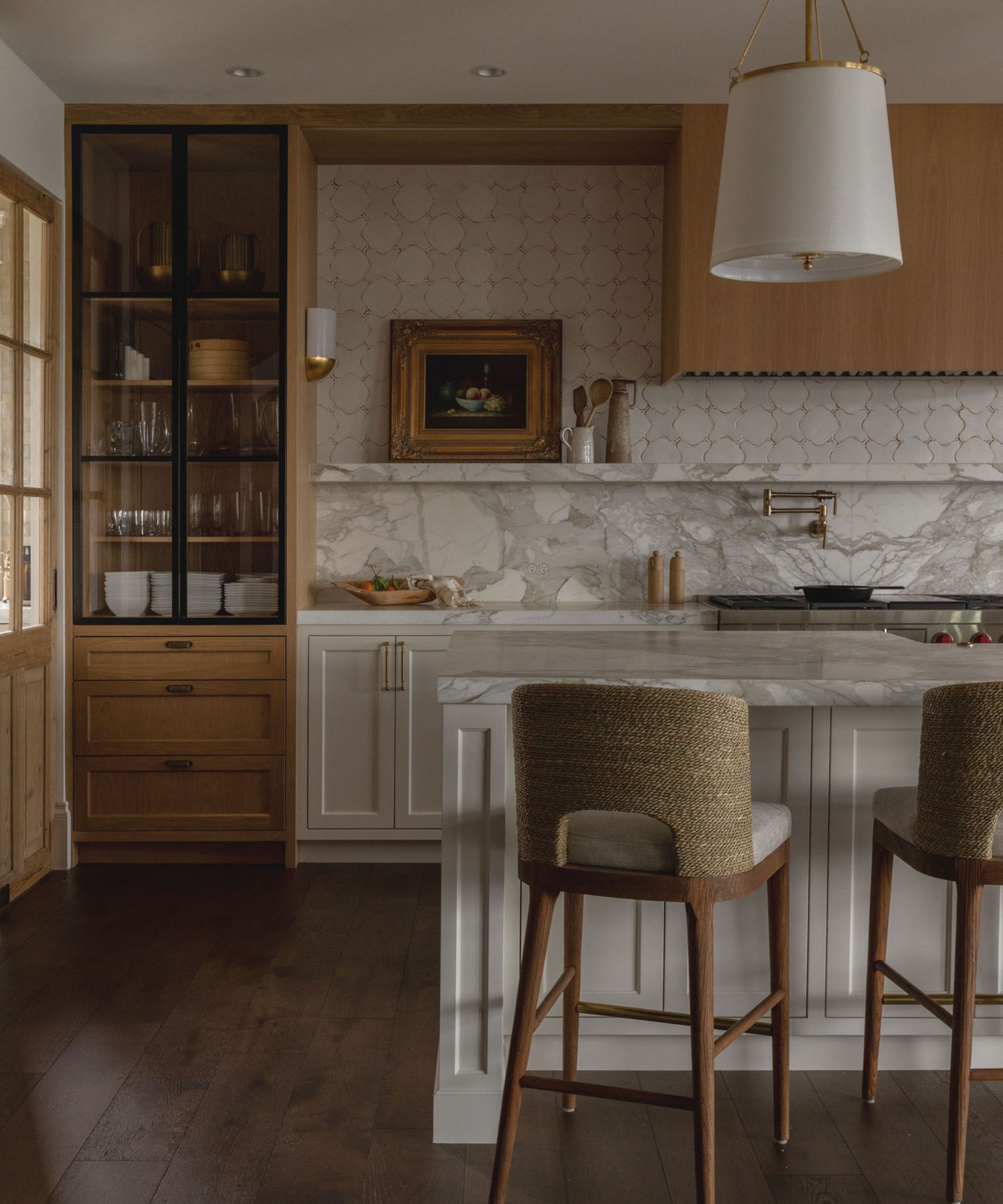 A warm kitchen with wooden cabinets, a marble countersplash which ends in a shelf, and a tiled wall to extend the backsplash to the ceiling