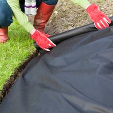 Woman lays down landscape fabric