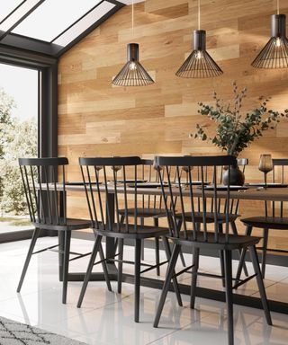 Modern country dining space with charcoal dining table and spindle dining chairs, and wood wall paneling, and wire conical pendants.
