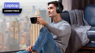 Man wearing Sony WH-1000XM4 wireless headphones drinking coffee in front of window