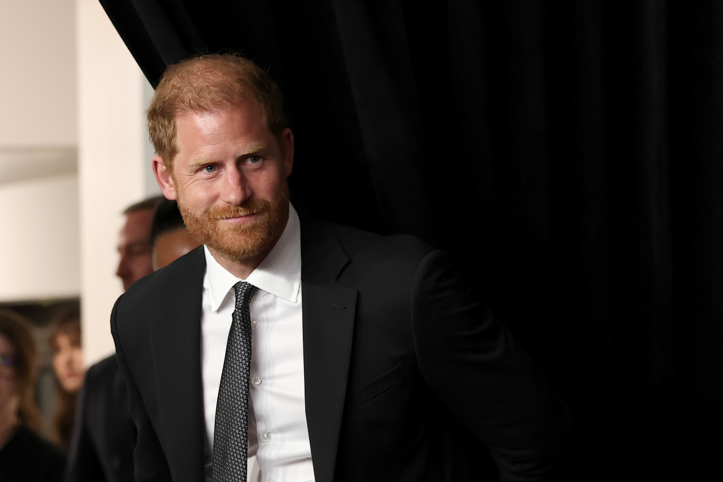 Prince Harry wearing a black suit and white shirt