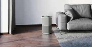 grey ivign room with a grey sleek air purifier on a wooden floor