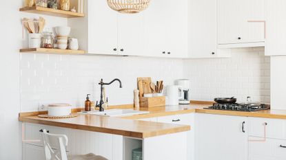 small white kitchen with wooden worktops and smart storage, demonstrating how to organize a small kitchen to maximize countertops and space 