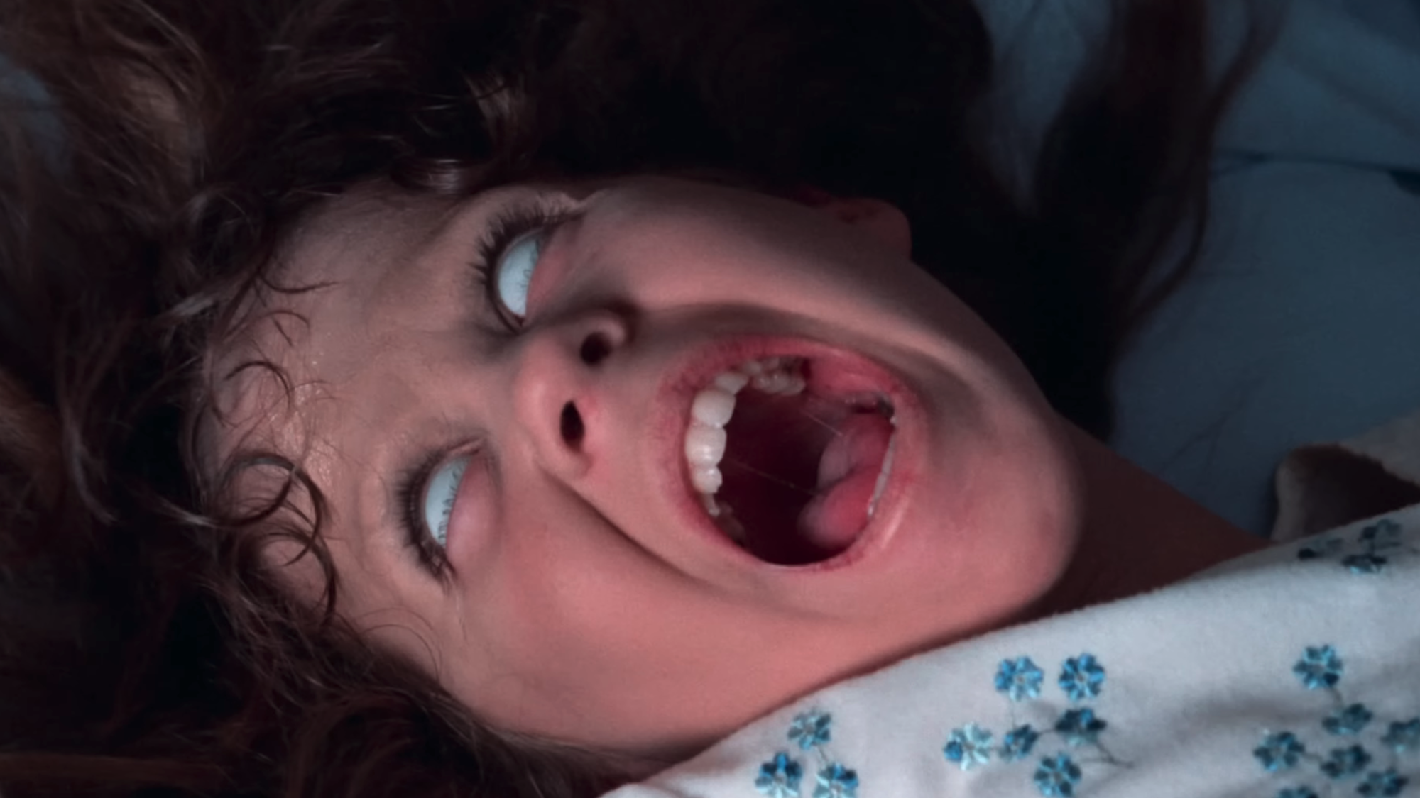 Linda Blair with white eyes while screaming in The Exorcist
