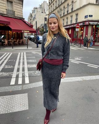 Woman in gray knit set and burgundy accessories