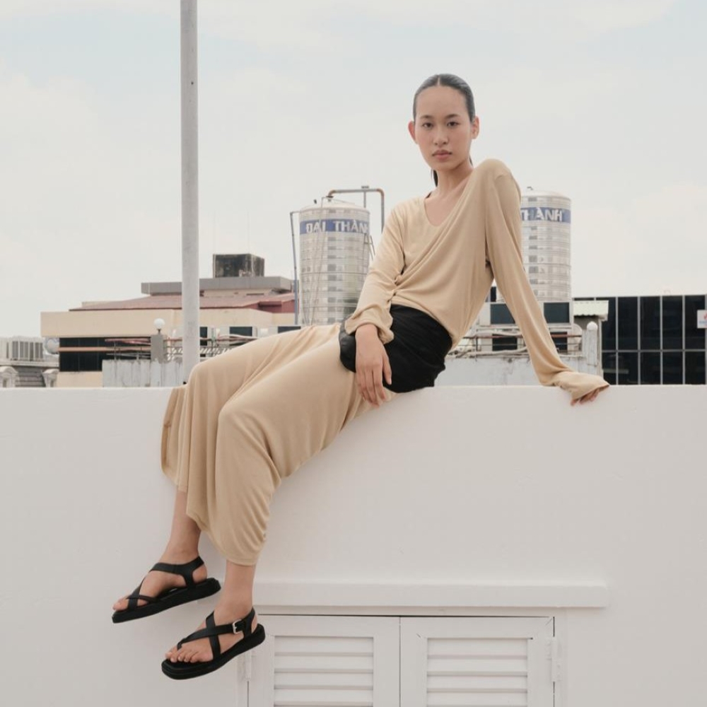 Model sat on a wall wearing Vagabond black sandals