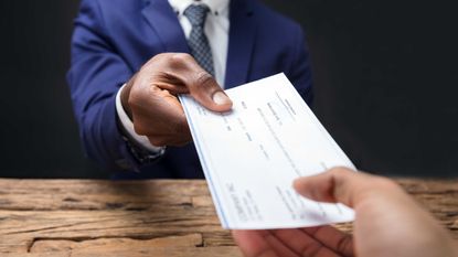 Person handing another person a paycheck