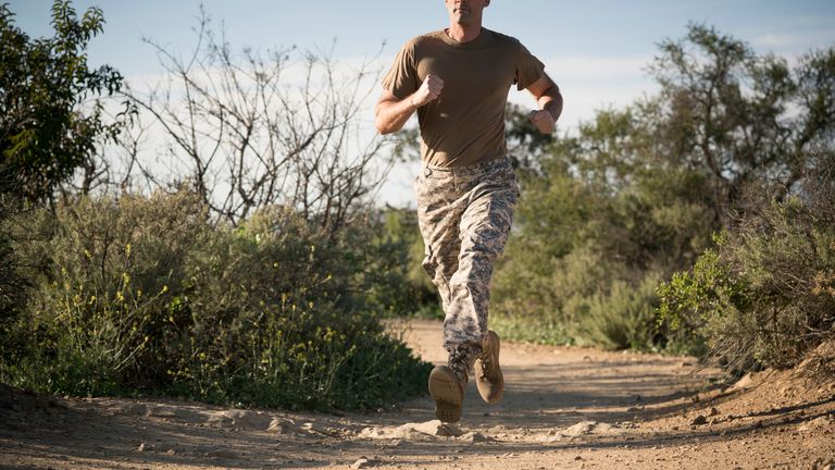 Man in military style uniform runs along a trail