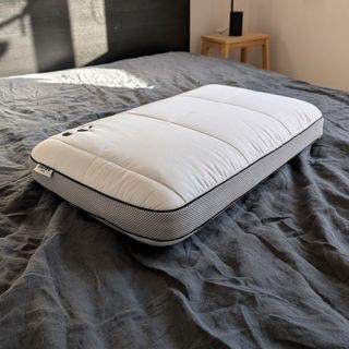 The Panda Hybrid Bamboo Pillow on a bed with a grey linen duvet cover