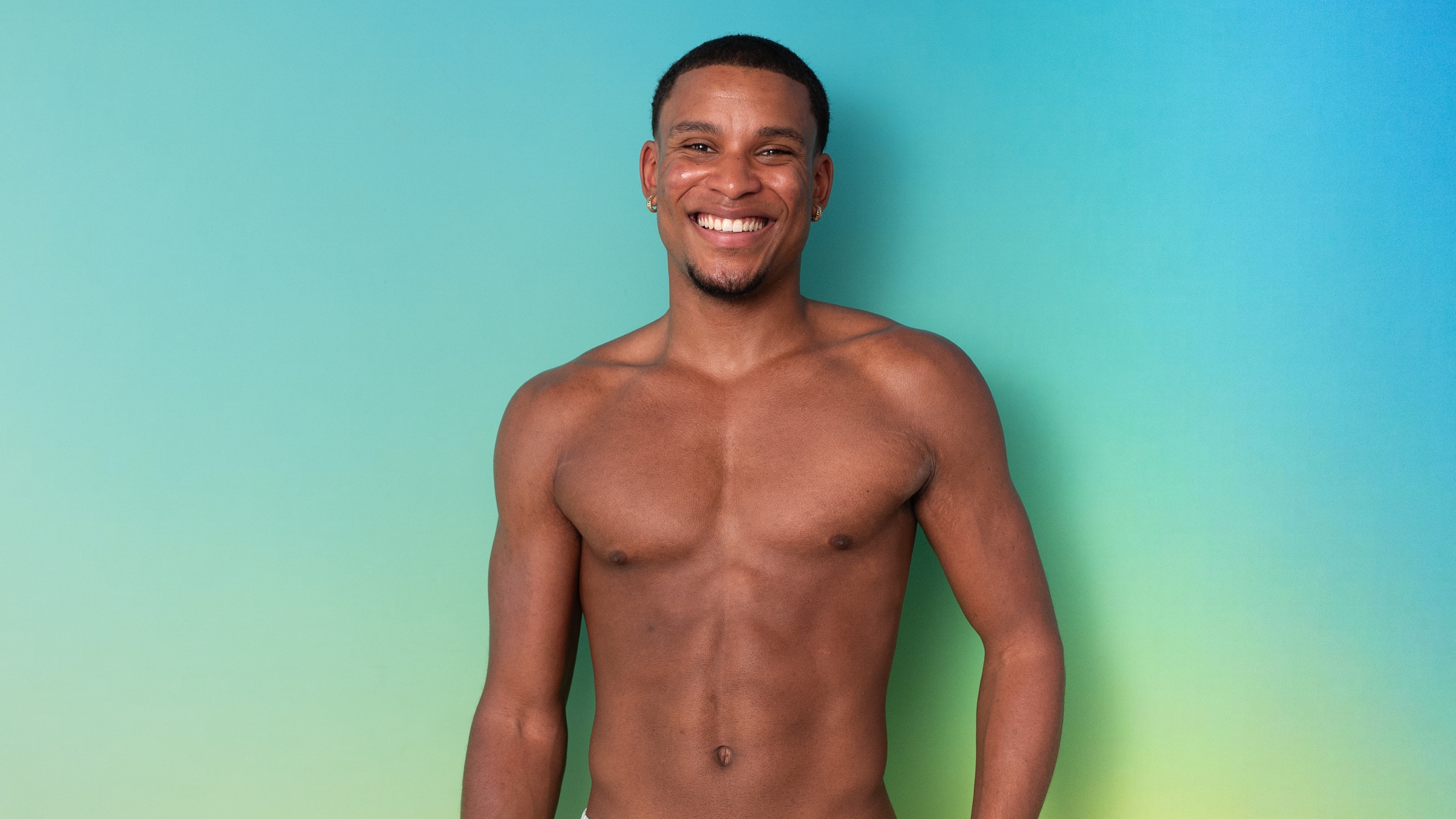 Cacherel standing in swimwear in front of a green background.