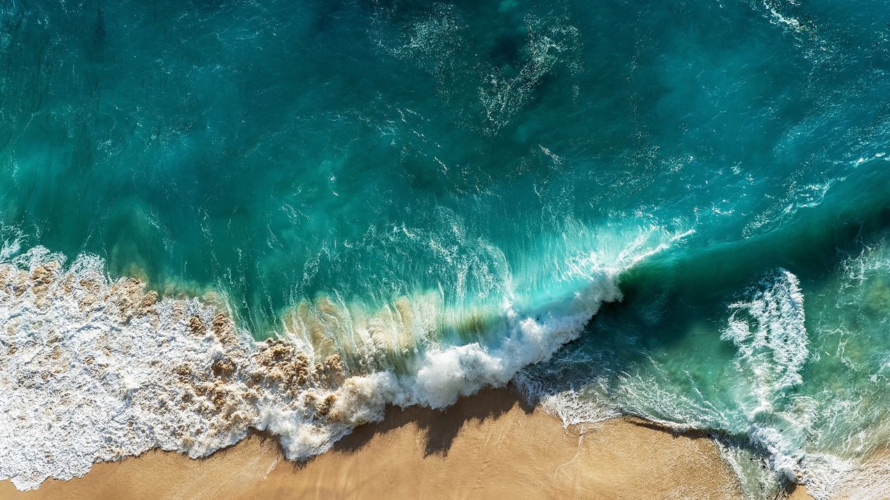 sustainable beauty brands: bird&#039;s eye view of crashing waves on the beach