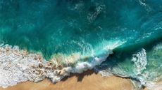 sustainable beauty brands: bird's eye view of crashing waves on the beach