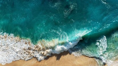 sustainable beauty brands: bird's eye view of crashing waves on the beach