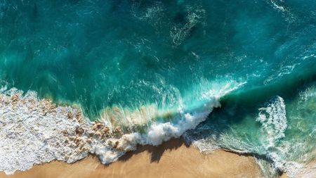 sustainable beauty brands: bird's eye view of crashing waves on the beach