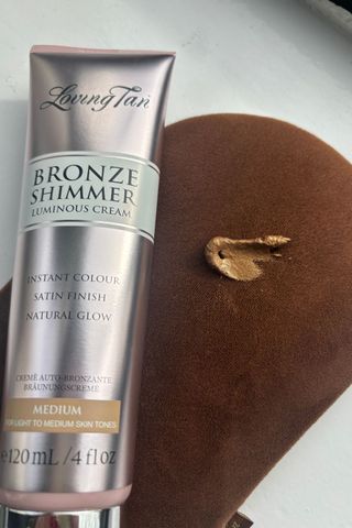 a tube of loving tan luminous cream next a smear of the cream