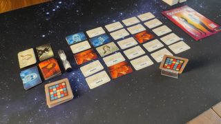 Codenames cards laid out in a grid, with the rulebook to one side, on a starry background