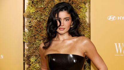 Kylie Jenner in black dress, gold background