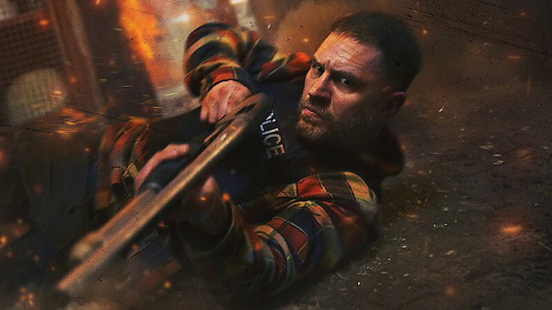 Tom Hardy on the floor holding a shotgun