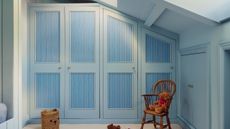 A row of blue built-in closets in a room with a pitched roof. 