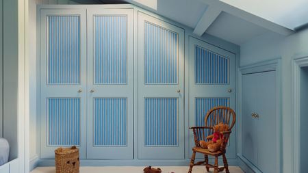 A row of blue built-in closets in a room with a pitched roof. 