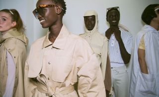 Models wear beige trench coats and white shirts