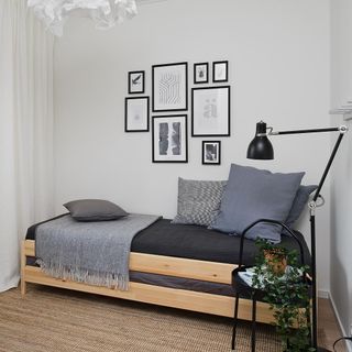 bedroom with white wall wooden bed with cushion frames on wall