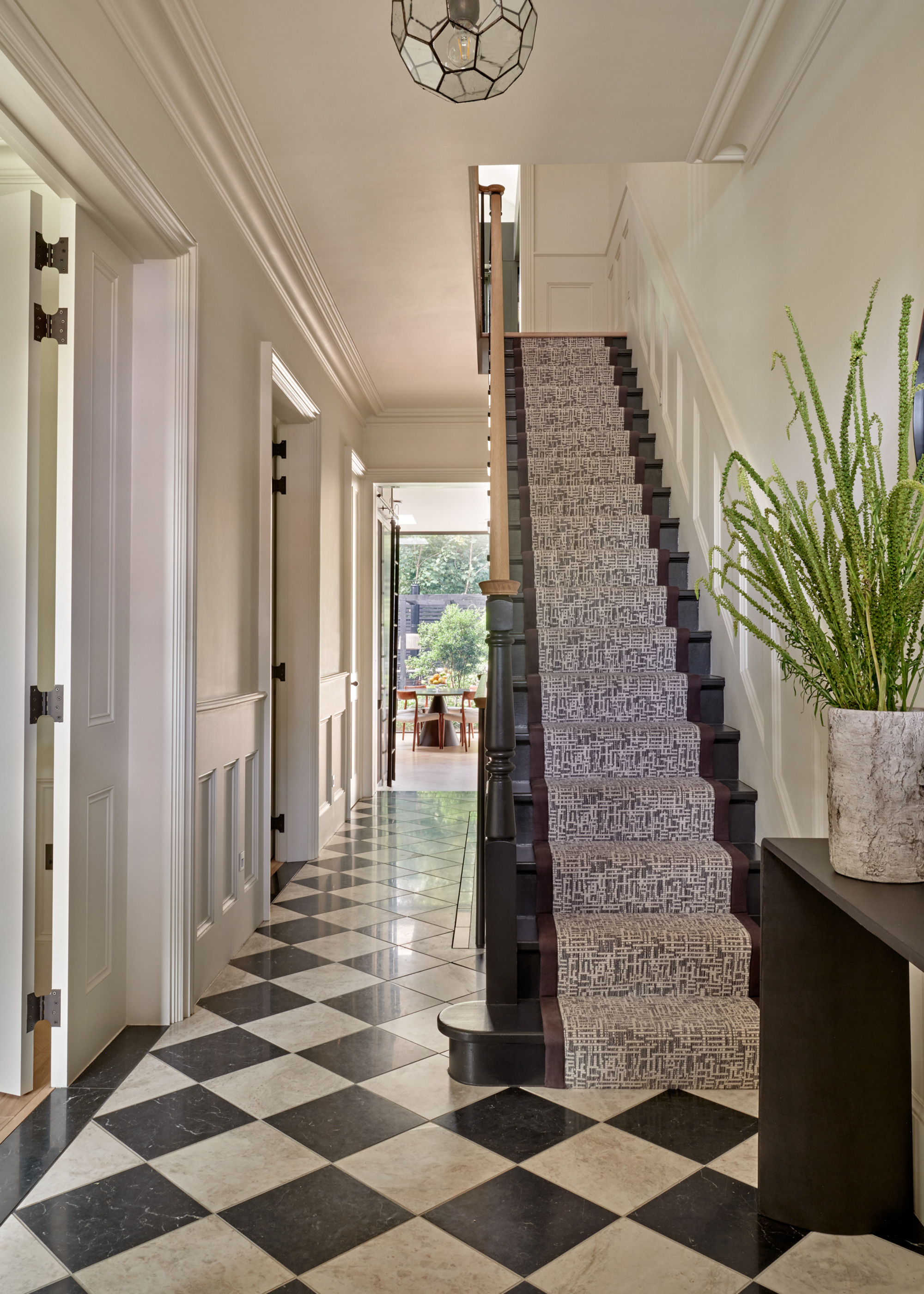 Hallway with marble chequered flooring and black and white stair runner