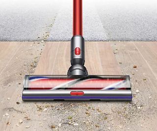 Dyson vaccum floorhead vacuuming dirt from a hard floor and carpet