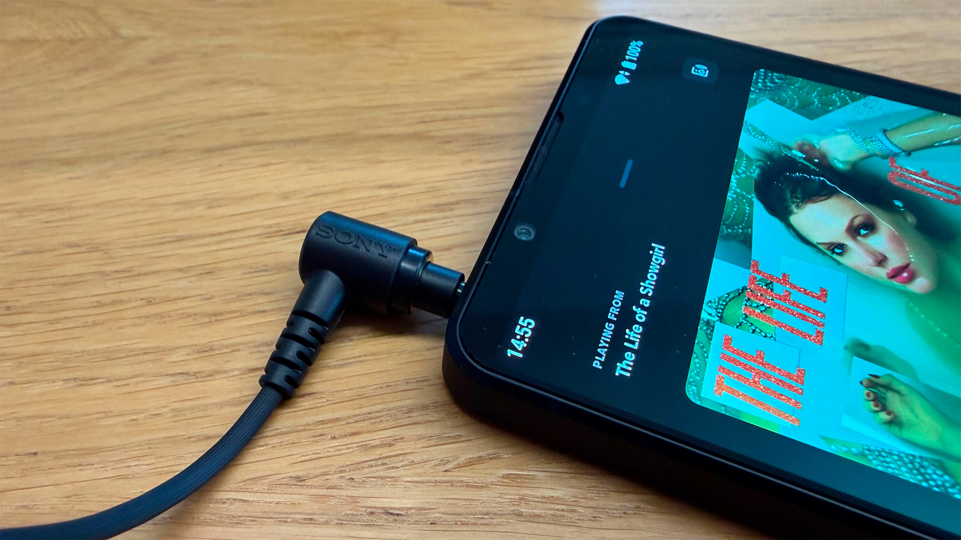 Sony Xperia 1 VII smartphone on wooden surface detail of top of phone with headphone cable plugged in