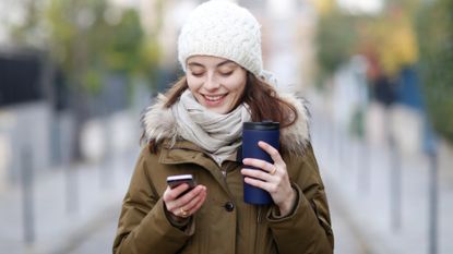 Young woman in coat scarf and hat on cell phone
