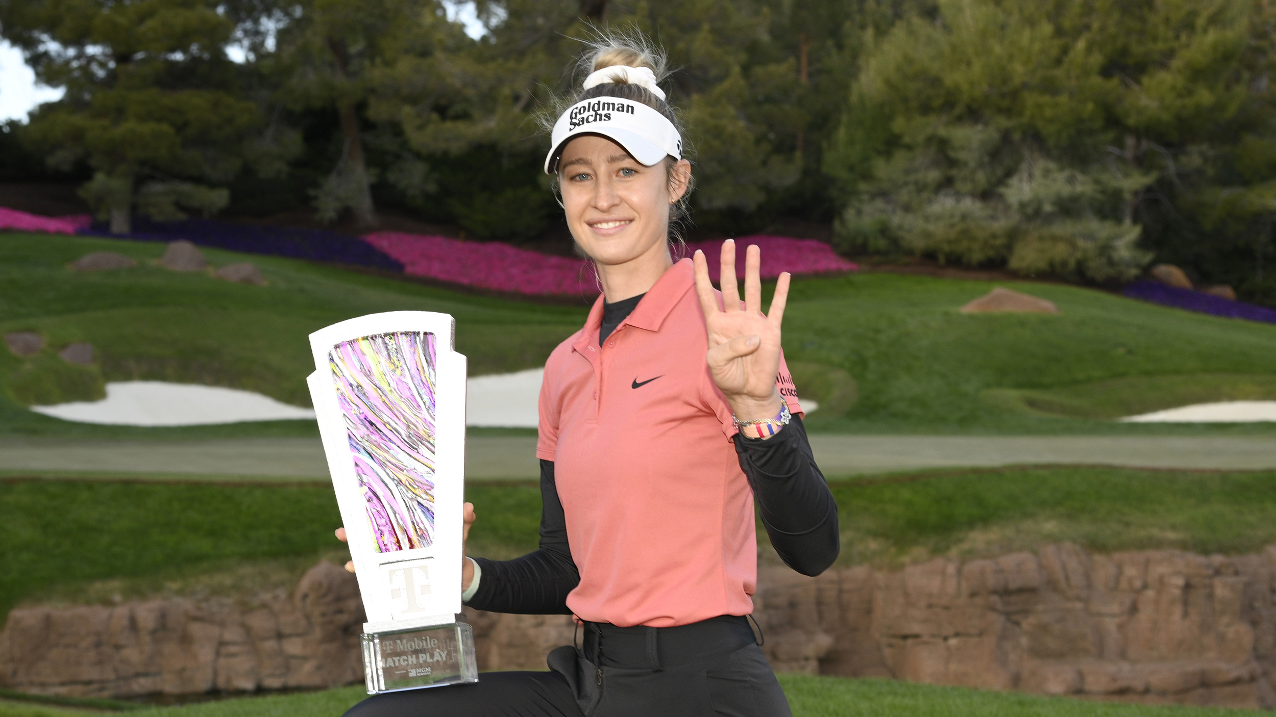 Nelly Korda with a trophy and holding up four fingers