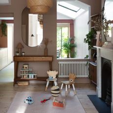 A soft brown-painted family living room with a hardwood console table and a central play area