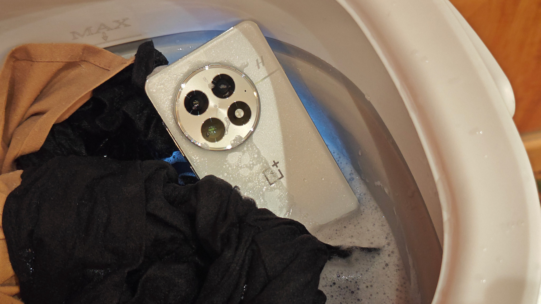 The IP69 certified white OnePlus 13 in a washing machine with clothes