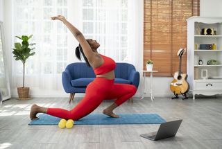 Benefits of yoga: African young woman doing yoga virtual fitness class with laptop at home - E-learning and people wellness lifestyle concept