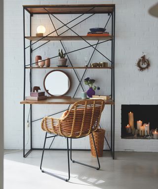 A home office with shelf unit and floating desk with rattan chair