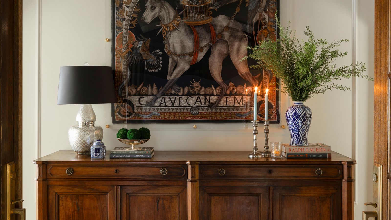 Entryway cabinet with lamp, candles and wall tapestry