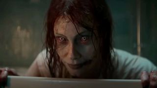 A possessed Ellie looks over a door frame in Evil Dead Rise