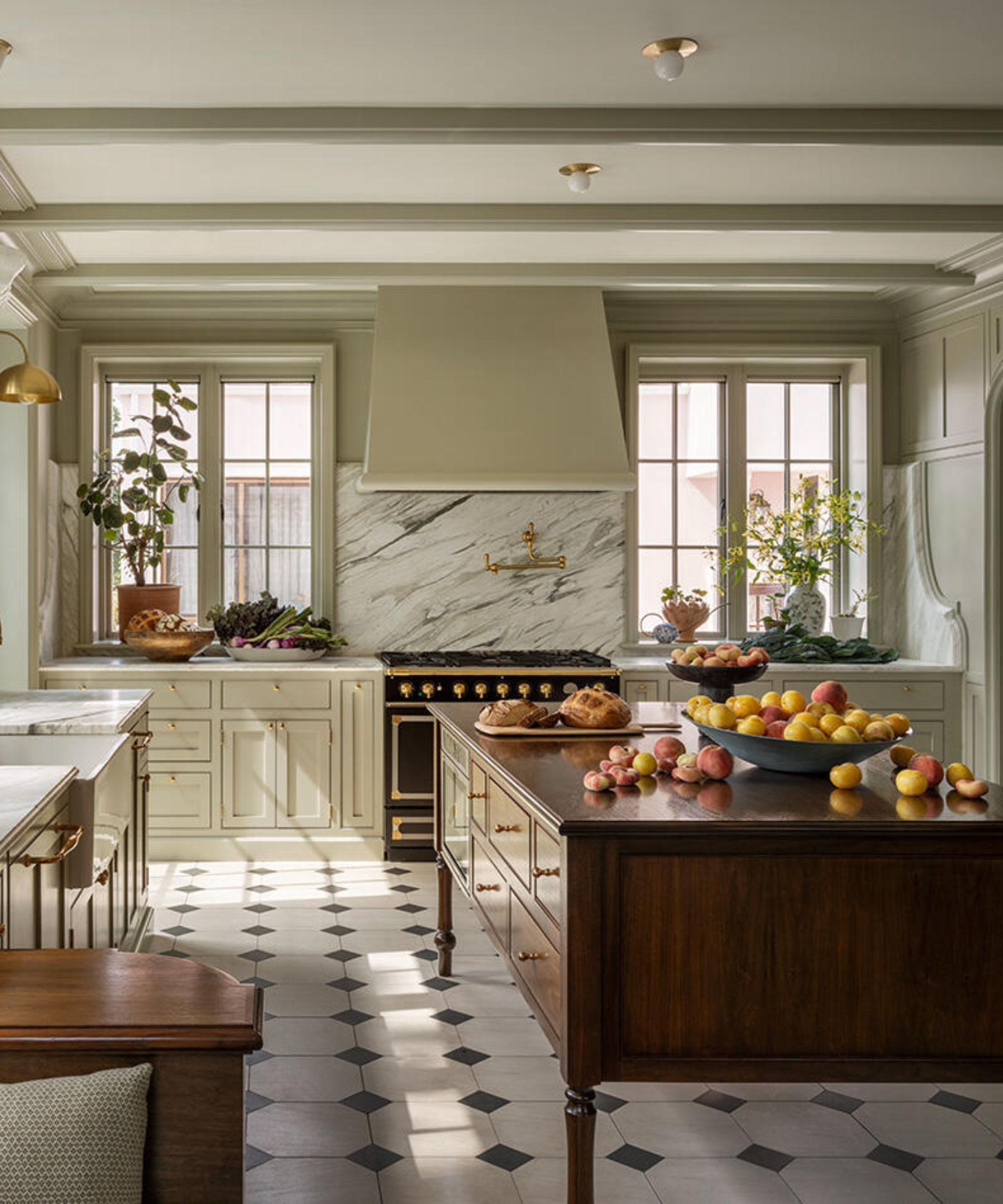 A light green kitchen with a wooden island and a marble backsplash and sidesplash