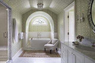 A bathroom designed with green, printed wallpaper